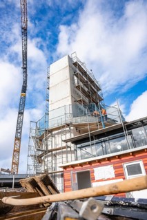 Construction site with large crane and scaffolding under a clear sky, extension of the Calw railway