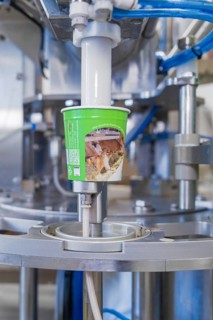 Machine filling process of a green ice cream cup in production, ice cream production Haselstaller