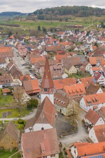 View of a village with a distinctive church tower, surrounded by traditional houses, children's