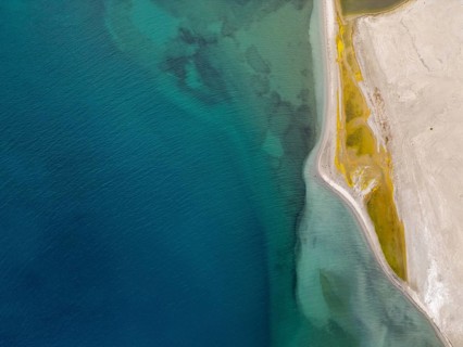 A striking aerial view of Pangong Tso in Ladakh, showcasing the contrasting colors of the deep blue