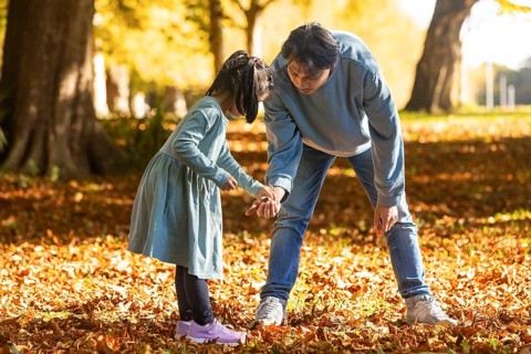 An Asian father and daughter enjoy quality time together in a beautiful autumn park, surrounded by