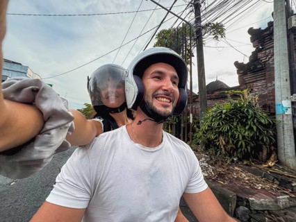 Smiling couple on a motorcycle ride, wearing helmets, capturing a happy moment on a selfie. Lush