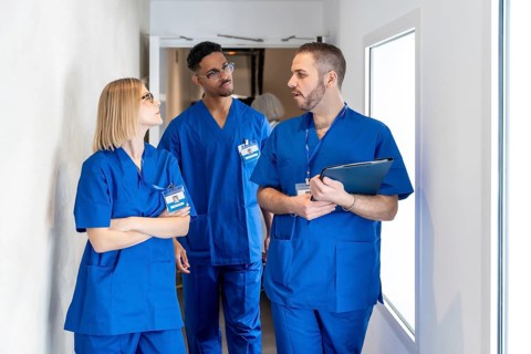Diverse medical team collaborating and communicating while walking through a bright hospital