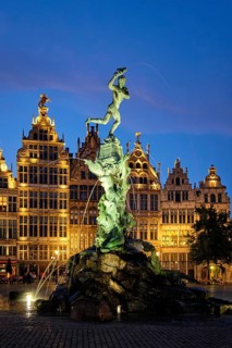 Antwerp famous Brabo statue and fountain on Grote Markt square illuminated at night and old houses.