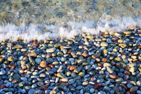 Waves hit a pebble beach creating texture and colors, Zero Waste Island, Tilos, Dodecanese, Greek