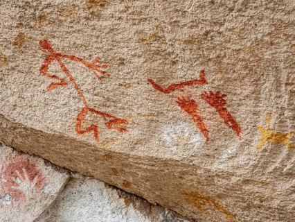 Colored hands and painted human being at the wall of the canyon, Cueva de las Manos, prehistoric