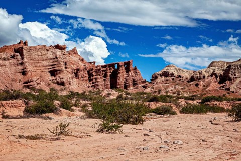 An extensive desert landscape with distinctive rock formations and an intense blue sky, the