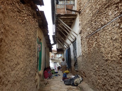 A narrow alley with traditional buildings and seated people, Harar, Ethiopia