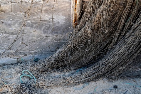 Close-up view of old fishing net hanging on boat, Oman