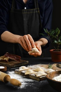 Hands skillfully shape traditional dumplings in a warm kitchen atmosphere. Flour covers the table,
