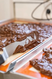 Chocolate mass spread with a spatula on a tray, Burch Schokolade production, Haselstaller Hof,