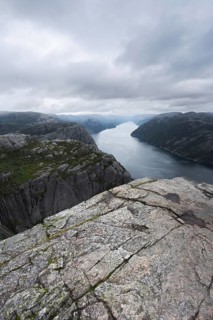 A breathtaking view of a Norwegian fjord framed by rugged cliffs under a cloudy sky, ideal for