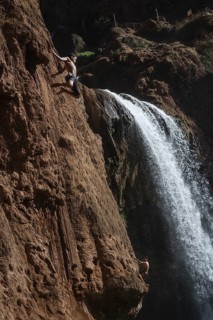 OUZOUD, MOROCCO - OCTOBER 5, 2024: A Moroccan young boy jumps from the high rock into the water