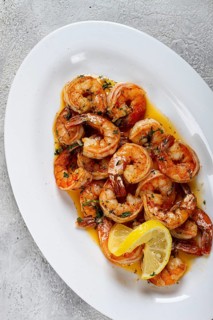 Fried tiger prawns, jumbo, in garlic sauce, in butter, with herbs, on a white plate, homemade, no