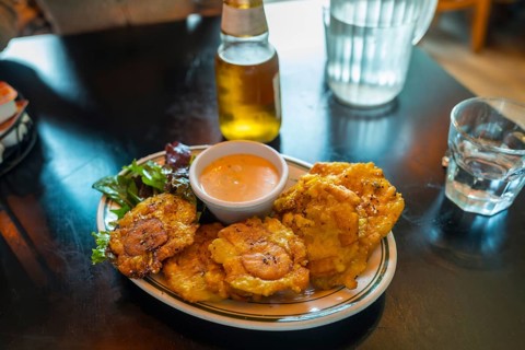 Fried plantain tostones served with a creamy dipping sauce and a side salad, creating a vibrant,