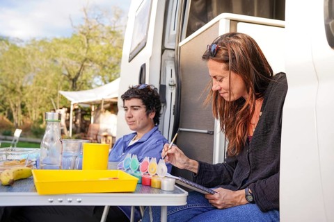 A lesbian couple enjoys time together at a motorhome campsite They relax, paint, and embrace the