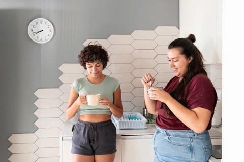 A loving lesbian couple enjoys a morning coffee together in their modern kitchen. They share smiles