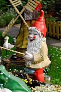Garden gnome fishing at a fish pond in spring in a front garden, Büdingen, Hesse, Germany