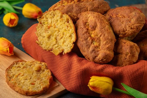Fresh potato rolls in a basket with orange cloth, one cut open