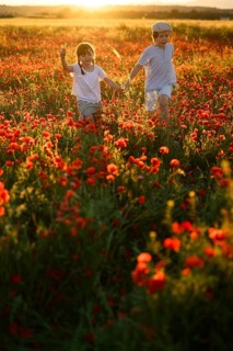 A young boy and girl, siblings, joyfully holding hands and running through a vibrant field of