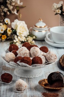 Decorative arrangement of chocolates on a porcelain dish, flowers and crockery in the background