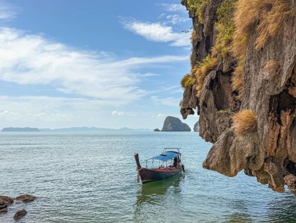 Breathtaking coastal views of Phuket, Thailand, featuring a traditional longtail boat gliding