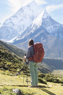 A woman in hiking gear admires the stunning view of the Himalayas, including Mount Everest, during