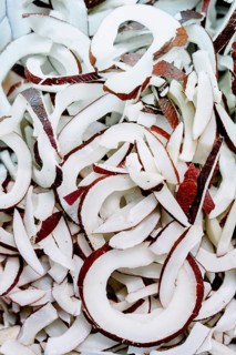 A close up of freshly sliced coconut pieces showcasing the contrast between the white flesh and