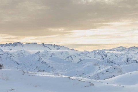 Serene beauty of a snowy mountain range at sunrise, where undisturbed snow blankets the peaks,