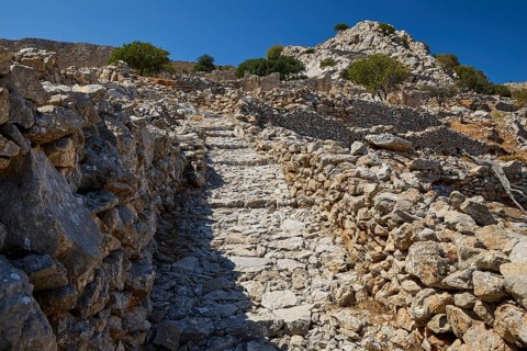 Old stone path leads through hilly terrain surrounded by stone walls and trees, Lost Place,