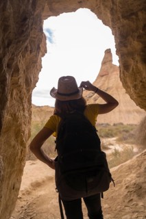 Vertical photo of the rear view of a woman into a cave in a desert
