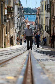 LISBON, PORTUGAL - MAY 19, 2025: Old man walks on the elevator tracks at the street Rua Da Bica