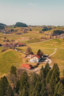 Idyllic alpine landscape with scattered houses and green hills under clear skies, Oberreute,