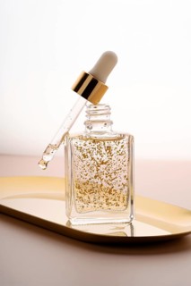 Elegant glass dropper bottle filled with anti-aging face serum, featuring suspended golden