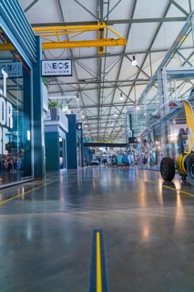 Spacious, modern room in industrial hall with steel structures and glass panes, warm yellow tones,
