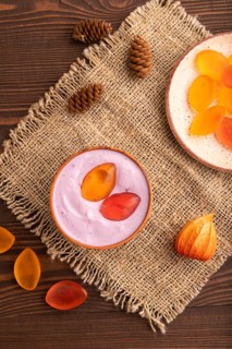 Purple Yogurt, with jelly candy on brown wooden background and linen textile, top view, flat lay,