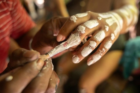 Tourists experience traditional body painting on Waigeo Island, Raja Ampat. This cultural art form