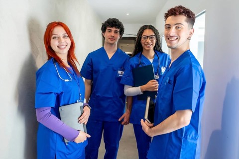 Diverse group of young medical students and healthcare professionals in blue scrubs smiling in a