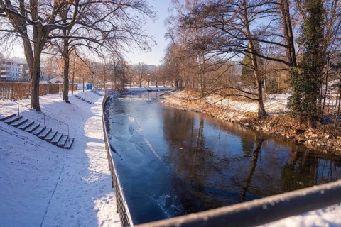 Snowy river landscape with bare trees and reflecting water under a clear sky, Nagold, Calw