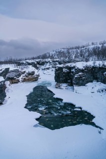 A striking view of a partially frozen river seamlessly cutting through the snow-covered terrain in