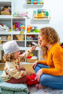 Vertical photo of a cute caucasian girl examining the tongue of her mother playing nurses