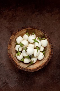 White mini eggplant, in a wooden bowl, on the table, close-up