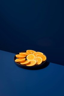 A plate of vibrant orange slices arranged neatly on a dark blue surface. The contrast highlights