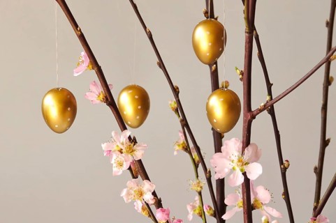 Blooming branches of a peach tree in a vase decorated with Easter eggs, spring, Germany