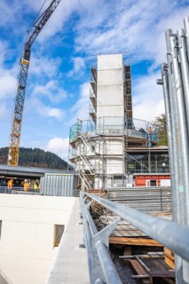 Unfinished building with scaffolding and crane at the edge of the construction site, extension of