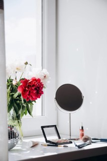 A vibrant bouquet of white and red peony flowers in a clear vase on a light-filled windowsill,