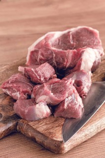 Raw beef meat, sliced on a cutting board, with a knife, no spices, no herbs, top view, wooden