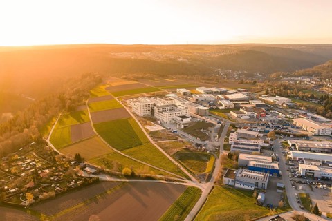 Comprehensive aerial view of a hilly landscape with buildings and fields in the evening light, new