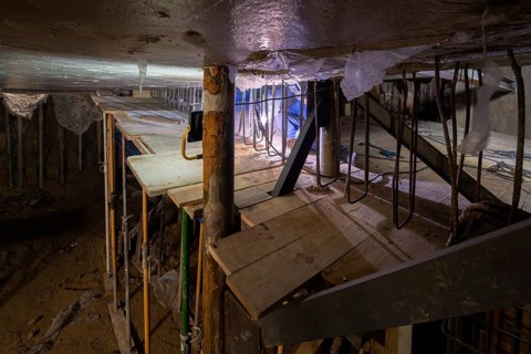 A detailed view of an underground construction site reveals complex scaffolding and steel