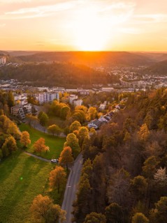 View of a hilly landscape with a town on the edge of a forest at sunset, Nagold, district of Calw,